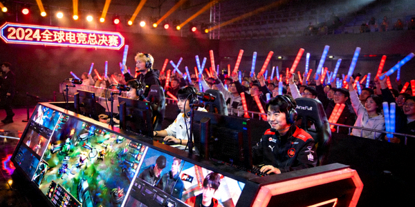 电竞比赛现场，选手在巨大屏幕前操作，观众欢呼